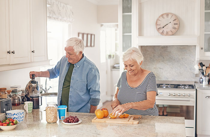 Happy senior couple preaparing a healthy breakfast in their kitchen