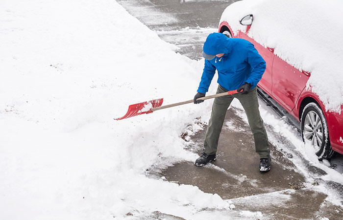 Person digging out their car from a snow storm.