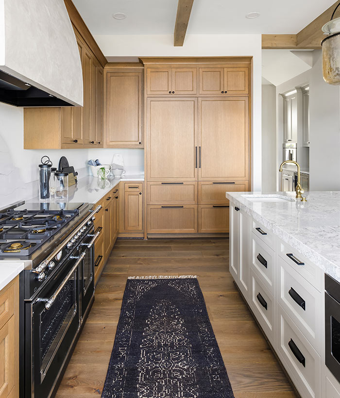 Kitchen detail in new luxury home. Features large island with faucet, large gas range and oven, large range hood and built in refrigerator.