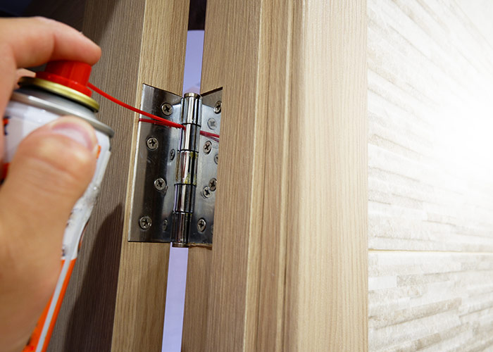 A man lubricates door hinges with oil