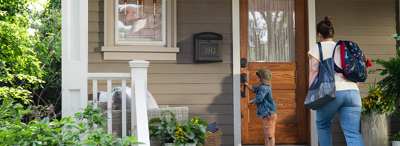 Child opening home front door for their mom whose hands are full.