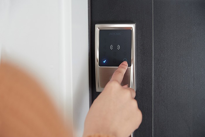 person entering code on smart lock