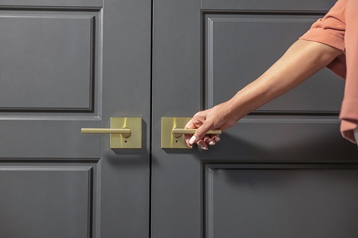 Woman reaching for Schlage custom latitude lever door handle on closet doors. 