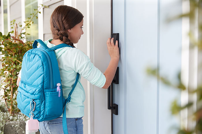 girl with backpack entering home