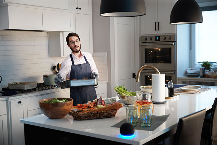 man cooking dinner speaking to amazon alexa speaker 